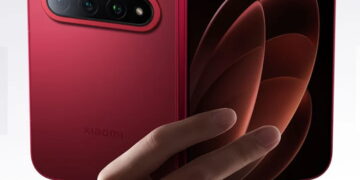 دست کاربر گوشی تاشو قرمز Xiaomi 18 Fold را در حالت نیمه‌باز نگه داشته؛ از پشت ماژول دوربین سه‌گانه و لوگوی Xiaomi و از رو، نمایشگر داخلی با والپیپر انتزاعی نارنجی دیده می‌شود.