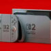 رندر کنسول Nintendo Switch 2 با کنترلرهای Joy-Con رنگی روی پس‌زمینه قرمز پررنگ که طراحی جدید و تغییریافته دستگاه را در مقایسه با نسل قبلی به نمایش می‌گذارد.