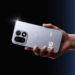 یک دست که گوشی OnePlus 16 نقرهای را افقی نگه داشته در پسزمینه ستارهای تیره؛ نمای پشت گوشی با ماژول دوربین دایرهای، طرح موج مشبک و عدد درخشان 16 روی بدنه.