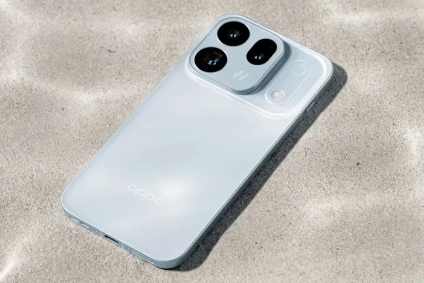 نمای ایزومتریک از گوشی هوشمند Oppo Find X10 Pro Max با رنگ بدنه روشن و شیشه‌ای که روی بستری از شن‌های ساحلی قرار گرفته و ماژول دوربین سه‌گانه برجسته آن با برند هاسلبلاد (Hasselblad) در پشت گوشی خودنمایی می‌کند.