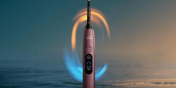 مسواک برقی هوشمند Philips Sonicare به رنگ برنزی متالیک همراه با خطوط نورانی آبی و طلایی چرخان در اطراف سری مسواک