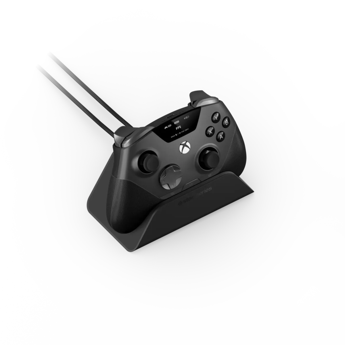 رندر استودیویی زاویهدار از دسته بازی مشکی SteelSeries Aeon Pro قرارگرفته روی پایه شارژ خاکستری؛ نمایشگر کوچک OLED بالای دسته با نشانگر پروفایل FPS و باتری، دو کابل بافتهشده متصل به بخش بالایی و لوگوی SteelSeries روی استند در پسزمینه یکدست مشکی.