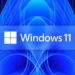 تصویر شاخص ویندوز ۱۱: لوگوی سفیدرنگ چهارخانهی مایکروسافت در کنار واژهی «Windows 11» روی یک نوار افقی آبی بلوری در مرکز کادر نشسته است. پسزمینه پسزمینهی رسمی «Bloom» ویندوز ۱۱ است؛ الگویی متقارن و گلمانند از پردههای موجدار و رشتههای نوری آبی و سرمهای که از مرکز به بیرون باز شدهاند. واترمارک «Neowin» در گوشهی پایین سمت راست دیده میشود.