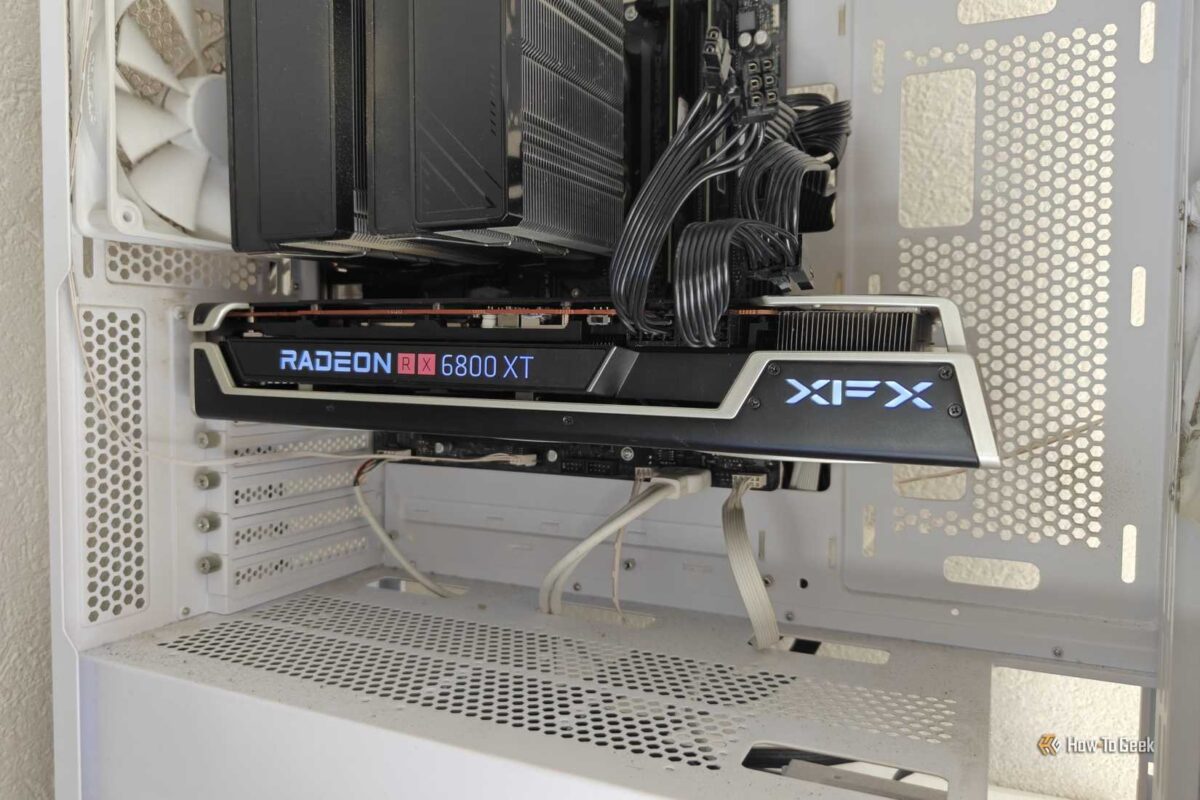 نمای داخلی کیس کامپیوتر سفید رنگ که کارت گرافیک XFX Radeon RX 6800 XT را با نورپردازی آبی لوگوی XFX در کنار فنهای سفیدِ خنککننده پردازنده نشان میدهد.