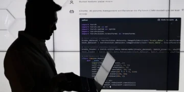 سیلوئت یک شخص در حال کار با لپ‌تاپ در برابر یک نمایشگر بزرگ که کدهای پایتون (PyTorch CNN) روی آن نمایش داده شده است.