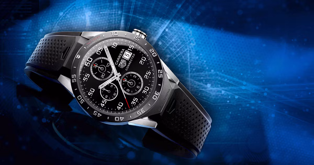 ساعت هوشمند مشکی TAG Heuer Connected با بند سیلیکونی سوراخدار، صفحه کرنوگراف دیجیتال و بدنه تیتانیومی روی پسزمینهای با طرحهای گرافیکی آبیرنگ قرار دارد.