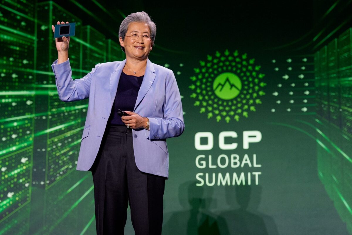 لیزا سو، مدیرعامل AMD، روی صحنه همایش OCP Global Summit در حالی که کت بنفش به تن دارد و تراشه پردازنده سرور را با دست بالا گرفته است.
