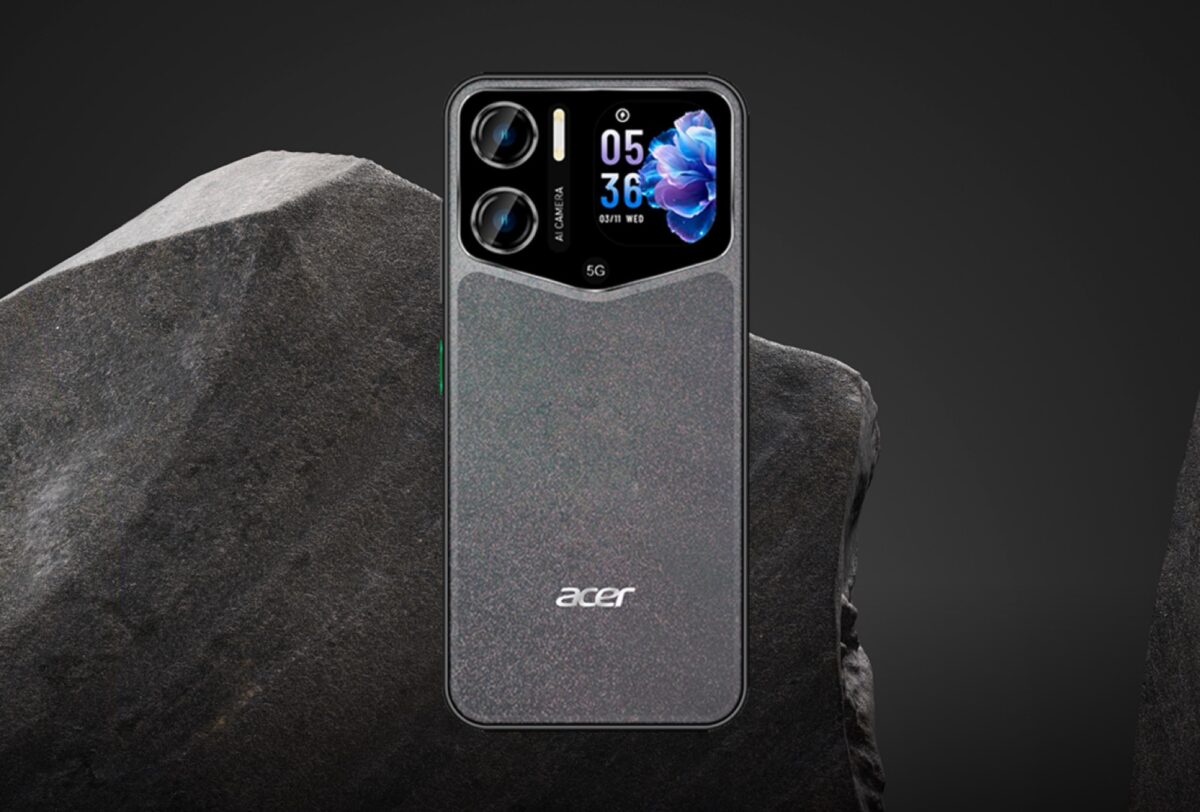 نمای پشت گوشی Acer Sospiro A70 با بدنه خاکستری بافتدار، دوربین دوگانه، نمایشگر کوچک روی مجموعه دوربین و نشان 5G؛ گوشی در برابر پسزمینهای از سنگ تیره قرار گرفته است.