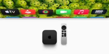 دستگاه Apple TV مشکی‌رنگ و ریموت کنترل آن روی سطحی سفید در کنار بخشی از تلویزیون که رابط کاربری tvOS و آیکون برنامه‌های مختلف را نشان می‌دهد.