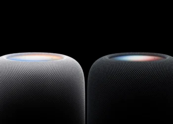 نمای نزدیک از بخش بالایی دو اسپیکر هوشمند HomePod اپل در رنگ‌های سفید و مشکی با پوشش پارچه‌ای مشبک و سطح لمسی نورانی رنگی در پس‌زمینه کاملاً سیاه.