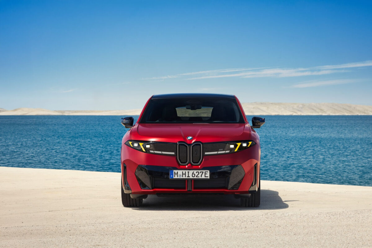 نمای روبهروی خودروی برقی BMW iX4 M60 قرمزرنگ با جلوپنجره دوگانه عمودی، چراغهای LED باریک و طراحی اسپرت در ساحل