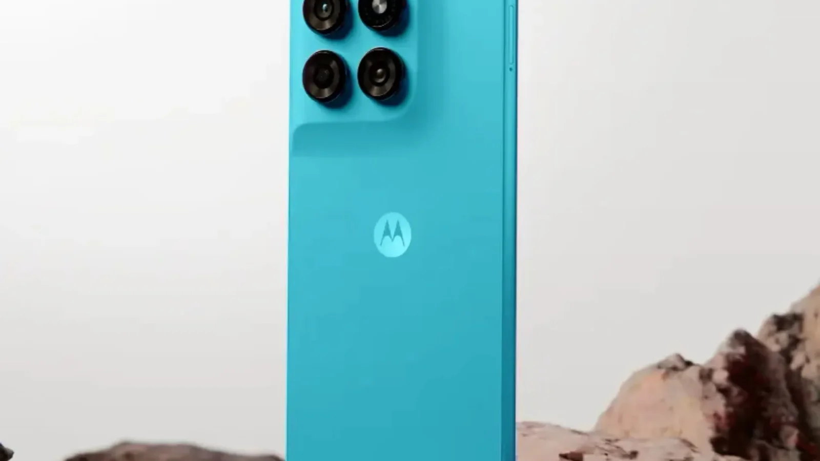 گوشی فیروزه‌ای موتورولا Moto G47 Power ایستاده روی سنگ در نمای پشت با دوربین چهارگانه و لوگوی موتورولا.