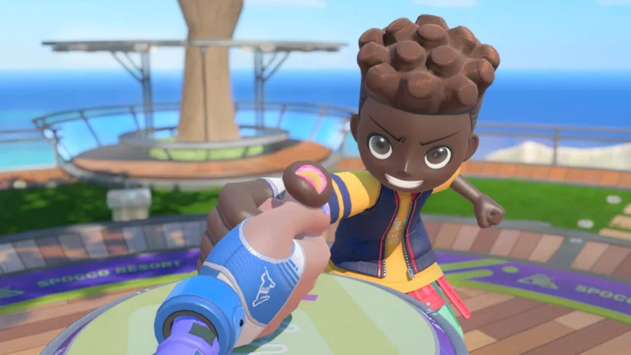نمایی از بازی Nintendo Switch Sports Resort و مسابقهی مچاندازی روی میز، با شخصیتی با موهای قهوهای در برابر دست کاربر با کنترلر آبی.