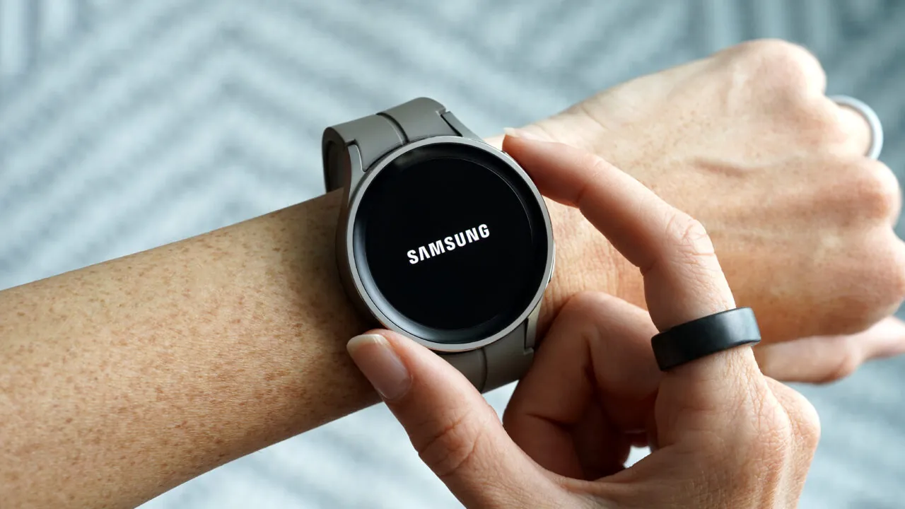 فردی ساعت هوشمند Samsung را روی مچ دستش لمس میکند و حلقهی هوشمند مشکیرنگی نیز در دست دیگر او دیده میشود.