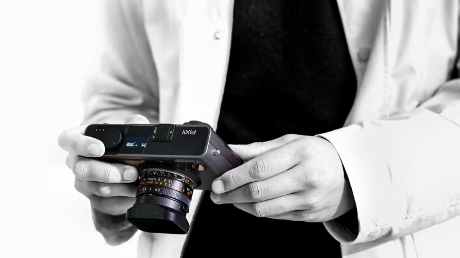 شخصی در حال نگهداشتن دوربین عکاسی مدرن Pixii با لنز متصل و نمای سیاهوسفید.