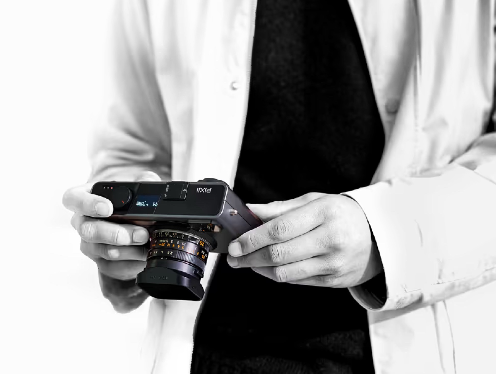 شخصی در حال نگه‌داشتن دوربین عکاسی مدرن Pixii با لنز متصل و نمای سیاه‌وسفید.