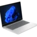 لپتاپ نقرهای رنگ HP ProBook روی میز با صفحهنمایش روشن و تصویر زمینه موجهای آبی رنگ ویندوز ۱۱.