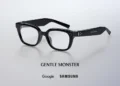 عینک هوشمند مشکی رنگ با دوربین روی دسته، بالای نوشته Gentle Monster و همکاری مشترک Google و Samsung روی پس‌زمینه خاکستری روشن.