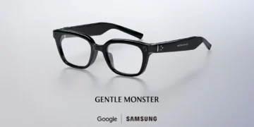 عینک هوشمند مشکی رنگ با دوربین روی دسته، بالای نوشته Gentle Monster و همکاری مشترک Google و Samsung روی پسزمینه خاکستری روشن.