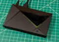 تی‌وی باکس Nvidia Shield TV Pro با بدنه مشکی، طراحی زاویه‌دار و خط نورانی سبز روی صفحه کار مدرج سبز