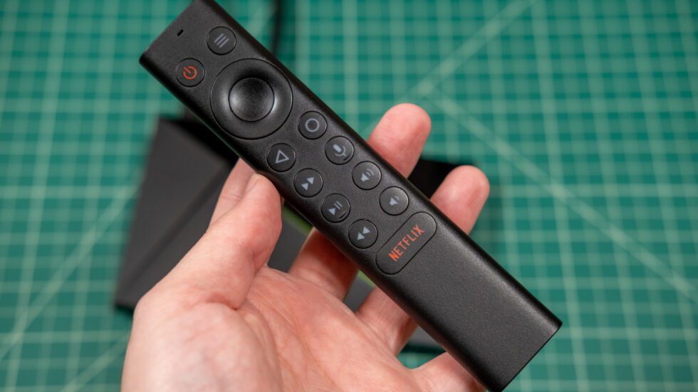 نمای نزدیک از ریموت کنترل مشکی و باریک دستگاه Nvidia Shield TV با دکمه اختصاصی نتفلیکس در دست کاربر