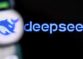 نمای نزدیک و تار از صفحه گوشی هوشمند که لوگو و نام آبیرنگ دیپسیک (DeepSeek) را بر روی پسزمینه مشکی نمایش میدهد.