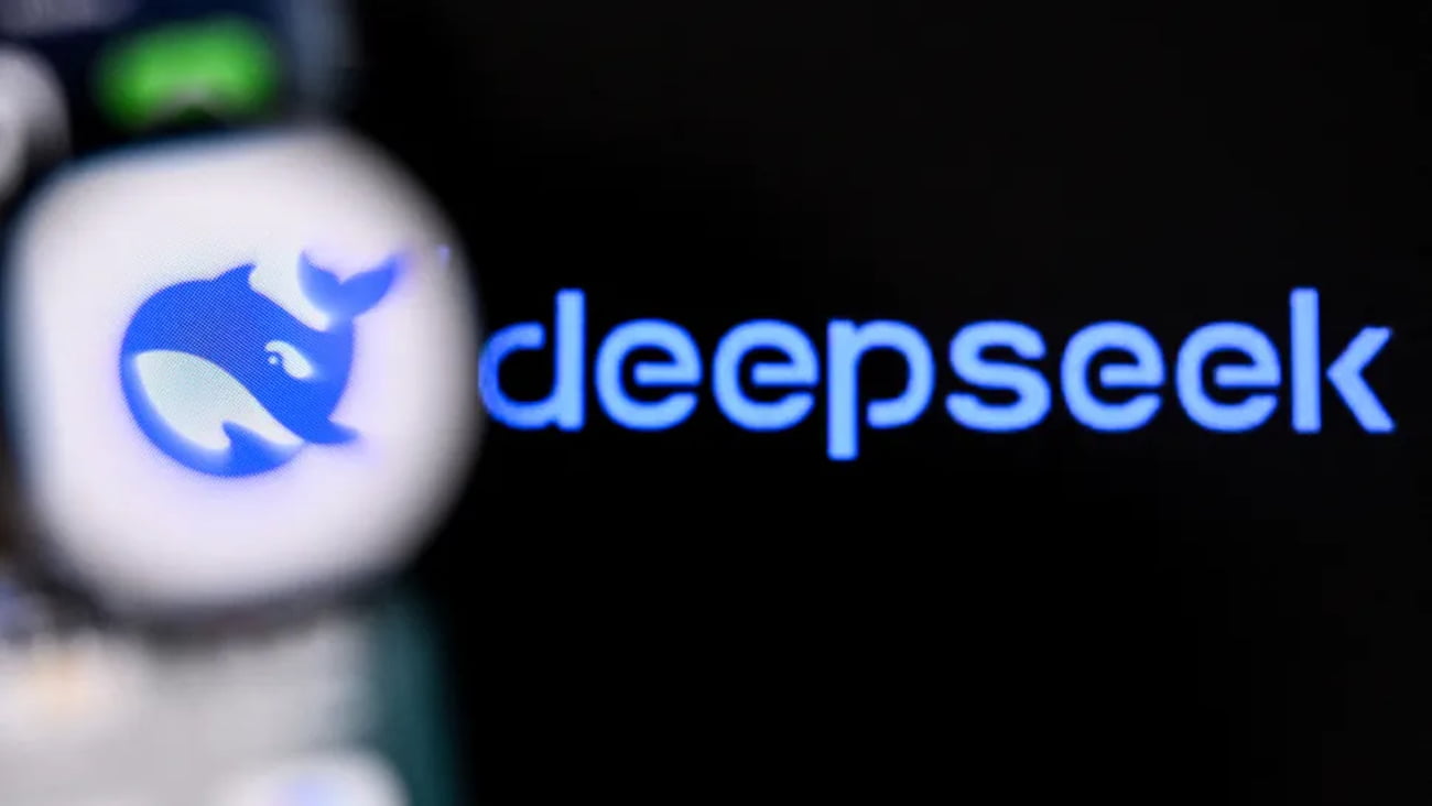 نمای نزدیک و تار از صفحه گوشی هوشمند که لوگو و نام آبیرنگ دیپسیک (DeepSeek) را بر روی پسزمینه مشکی نمایش میدهد.