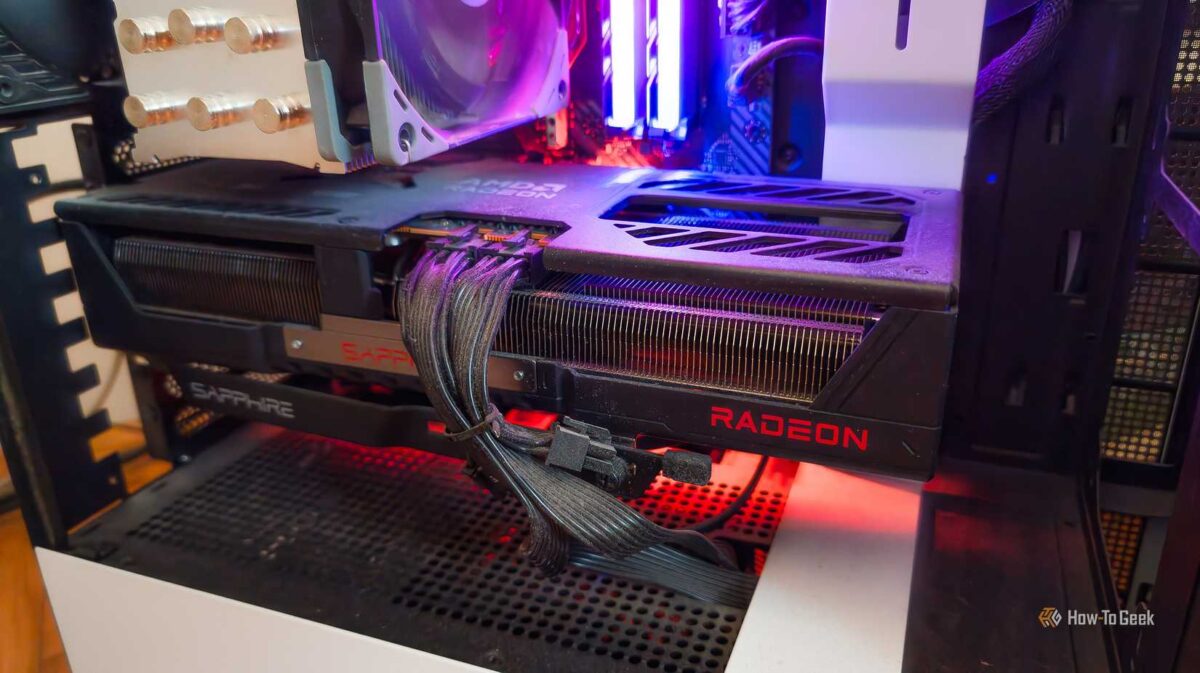 نمای داخلی کیس کامپیوتر با نورپردازی قرمز، که کارت گرافیک SAPPHIRE RADEON را با کابلهای برق مشکی متصل به آن در مرکز تصویر نشان میدهد.