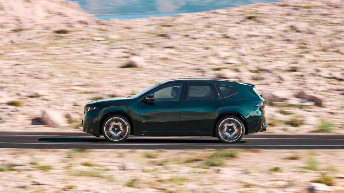 نمای جانبی شاسیبلند برقی BMW iX3 M60 xDrive سبز تیره با رینگهای آلیاژی بزرگ، سقف مشکی و طراحی آیرودینامیک در حال حرکت در جاده