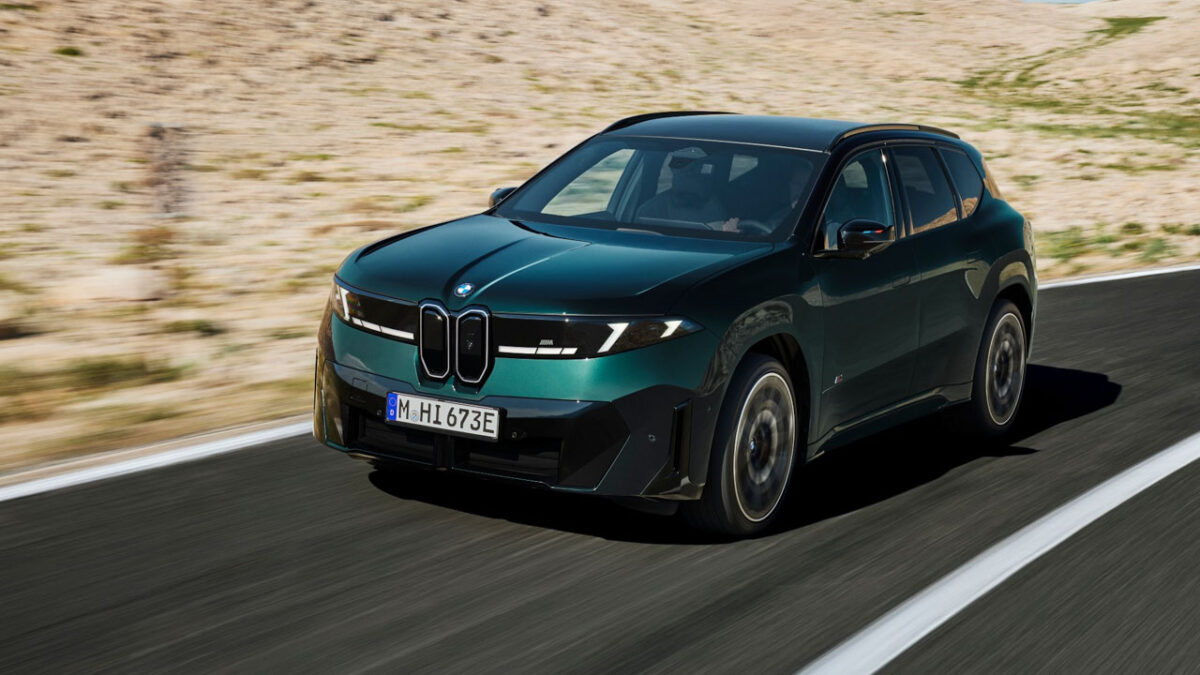 نمای سهرخ جلوی شاسیبلند برقی BMW iX3 M60 xDrive با جلوپنجره کلیوی، چراغهای LED و بدنه سبز تیره در حال حرکت در جاده