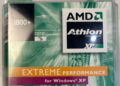 عکس بستهبندی قدیمی پردازنده AMD: نمای نزدیک از جعبه پلاستیکی پردازنده AMD Athlon XP با مدل 1800+ که روی آن لوگوی مشکی AMD Athlon، نوار نارنجی رنگ با عبارت «EXTREME PERFORMANCE» و برچسب «for Windows XP» روی پسزمینه سبز و موجدار دوران اوایل دهه ۲۰۰۰ دیده میشود.
