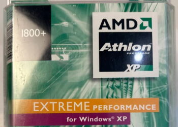 عکس بسته‌بندی قدیمی پردازنده AMD: نمای نزدیک از جعبه پلاستیکی پردازنده AMD Athlon XP با مدل 1800+ که روی آن لوگوی مشکی AMD Athlon، نوار نارنجی رنگ با عبارت «EXTREME PERFORMANCE» و برچسب «for Windows XP» روی پس‌زمینه سبز و موج‌دار دوران اوایل دهه ۲۰۰۰ دیده می‌شود.