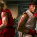 دو مبارز فیلم Street Fighter با لباس‌های سنتی قرمز و سفید در حالت رزمی و پشت به یکدیگر در یک سالن تمرینی ایستاده‌اند.