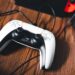 دستهی بیسیم DualSense کنسول PlayStation 5 با کابل شارژ روی سطح چوبی، در کنار نمای محو کنسول و یک Nintendo Switch
